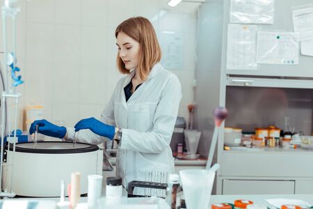 Blood testing equipment. Serious young woman standing near the centrifuge while conducting a blood...
