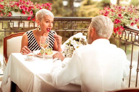 Wife eating salad. Wife wearing striped dress eating salad while having romantic dinner with husband outsideの写真素材