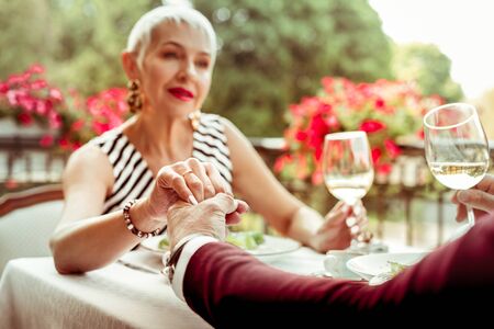 Wife and husband. Wife with bright pink lips touching hand of her supportive loving husbandの写真素材