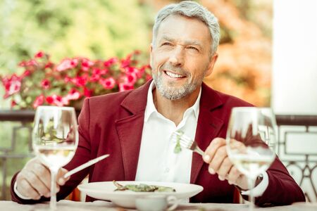 Wearing stylish jacket. Bearded grey-haired husband wearing stylish jacket having dinner outsideの写真素材