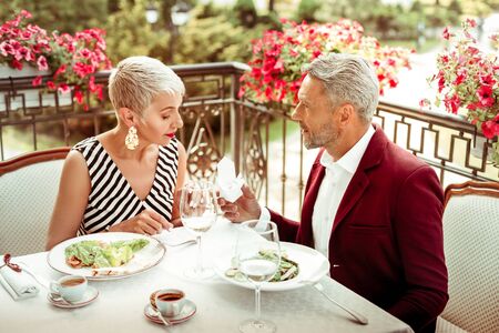 Presenting ring. Loving grey-haired husband presenting ring for wife while celebrating anniversaryの写真素材