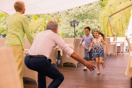 Meeting grandchildren. Grandparents standing on summer terrace meeting their grandchildren at the...