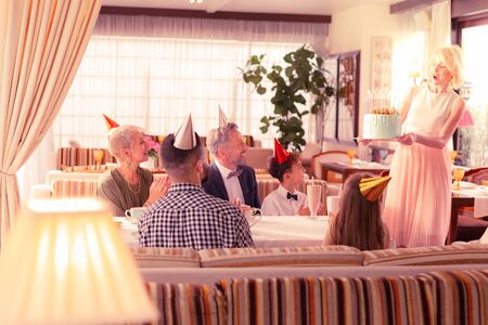 Bringing birthday cake. Blonde-haired happy mommy bringing birthday cake for her boyの写真素材