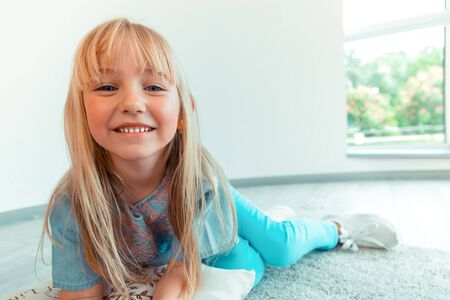 Carefree child. Face of a positive blonde girl while smiling to you