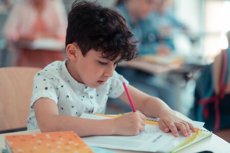Remembering lessons. Concentrated pupil of elementary school completing his maths test in class.の写真素材