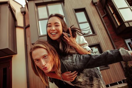 Stylish boyfriend. Strong supportive long-haired boyfriend having his dark-haired girlfriend on a...