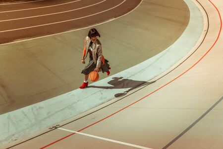 Active day. Delighted young woman playing with ball while having rest after her workの写真素材