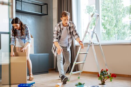 Unpacking boxes. Excited happy husband and wife unpacking boxes with things while movingの写真素材