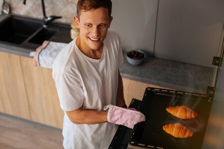 Tray with croissants. Husband loving cooking holding tray with just baked croissantsの写真素材