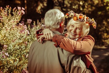 Two happy seniors hugging each other during their outdoor date in autumn park.の写真素材
