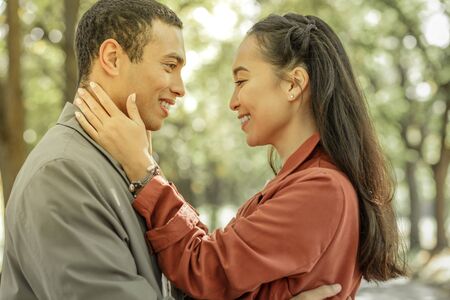 Short-haired caring man showing his feelings to appealing woman while staying in front of each otherの写真素材
