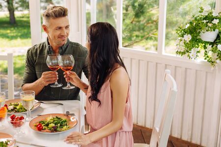 Couple having romantic lunch in summer house eating salads and drinking wine