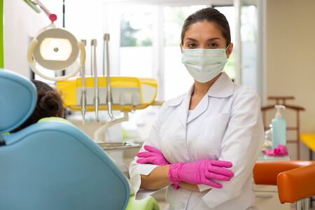 Green mask. Serious female doctor in a green mask standing with her arms crossed while looking at the cameraの写真素材