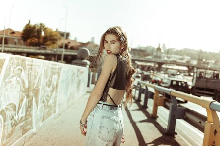 Demonstrating clothes. Nice-looking young lady turning her back to cameraman while wearing...
