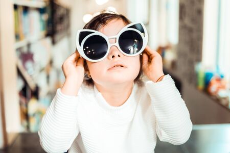 Stylish and fashionable . Little kid with down syndrome wearing big cat-shaped sunglasses for a unique lookの写真素材