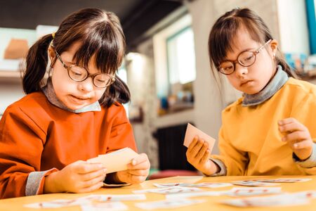 Learning alphabet. Diligent short-haired girls with mental problems being involved in a learning processの写真素材