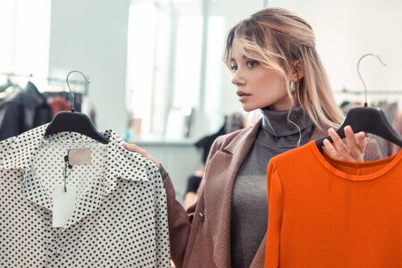 Woman shopping. Blonde-haired appealing young woman wearing grey polo neck and jacket shopping after workの写真素材