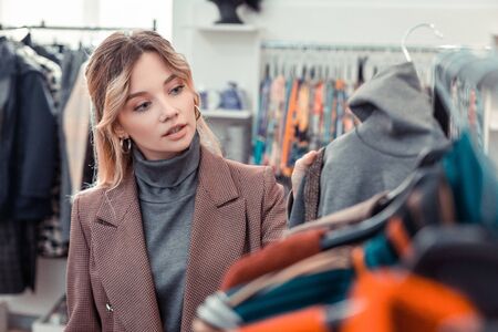 Choosing new clothes. Beautiful woman feeling joyful while shopping and choosing new clothesの写真素材