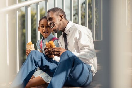 Enjoy your meal. Pretty little female expressing positivity while speaking with her daddyの写真素材