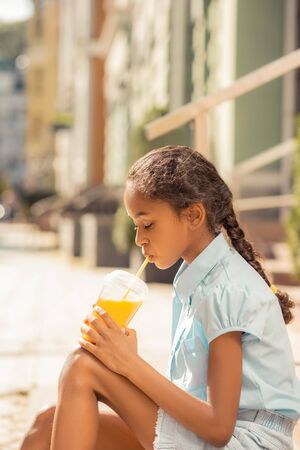 So serious. Attentive pupil bowing her head while drinking fresh juiceの写真素材