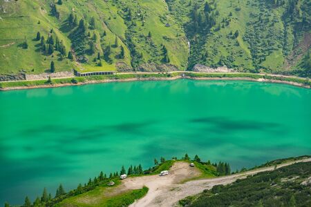 Beautiful nature with road near green hill and lake in Alps