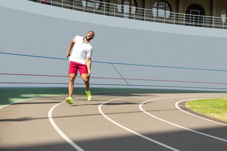 Knee pain. African American sportive young man suffering from sudden knee pain during the workout at...