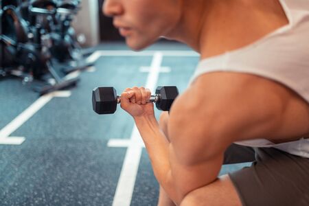 Training for muscles. Close up of a dumbbell being lifted by a handsome muscular manの写真素材