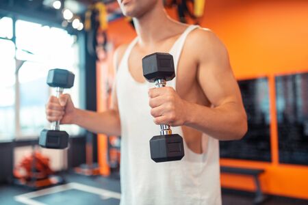 Workout equipment. Selective focus of a dumbbell being in male hands while working out in the gymの写真素材