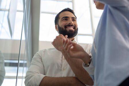 Having break. Cheerful bearded male person keeping smile on his face while listening to project presentationの写真素材