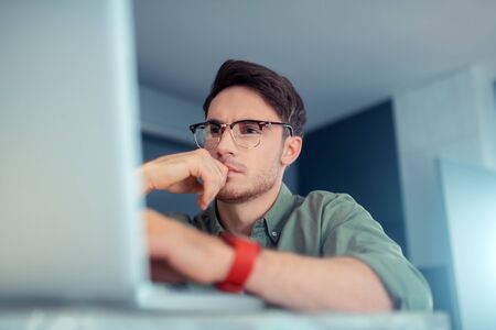 Businessman feeling busy. Handsome dark-eyed businessman feeling busy working on laptop