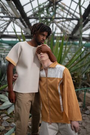 Talented models. Dark-skinned handsome talented model closing eyes of his colleagueの写真素材