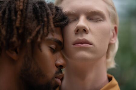 Two handsome men. Close up of two handsome men with different skin color closing eyes