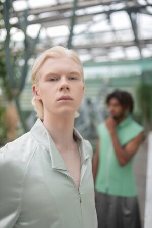 Blonde-haired model. Blonde-haired male model posing in greenhouse with African-American colleagueの写真素材