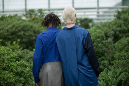 Near dark-skinned man. Blonde-haired man wearing blue shirt standing near dark-skinned manの写真素材