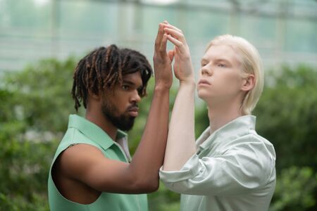Men touching hands. Men of different nationalities touching their hands while posing in greenhouse