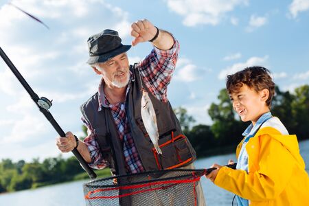 Fishing with granddad. Handsome excited boy feeling good while fishing with granddadの写真素材