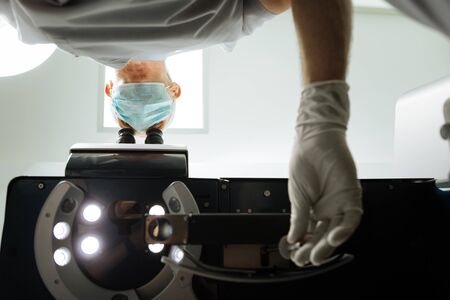 Setting the device. Low angle of a professional doctors hand while setting the device for eye...