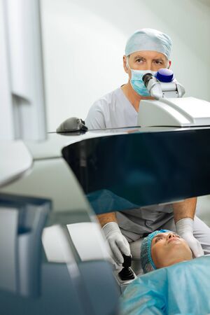 Nice mature man checking his patients eyesight while working in the hospital as a doctor