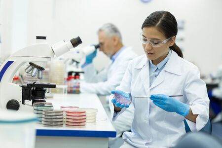 Sterile equipment. Pretty medical worker keeping smile on her face while checking DNA