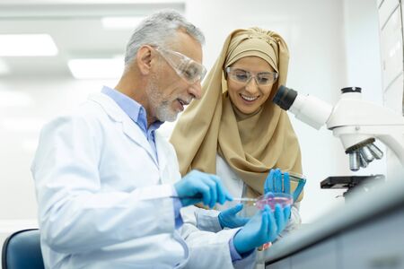 Good mood. Cheerful bearded man keeping smile on his face while doing DNA analysisの写真素材