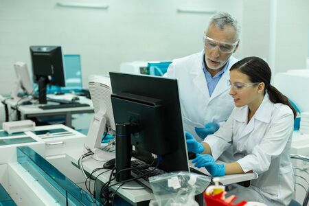 Technical research. Serious mature scientist wearing protective glasses while working in laboratory