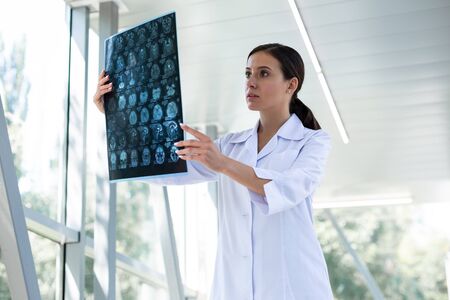 So serious. Pleased young scientist staring at X-ray photo and taking decision
