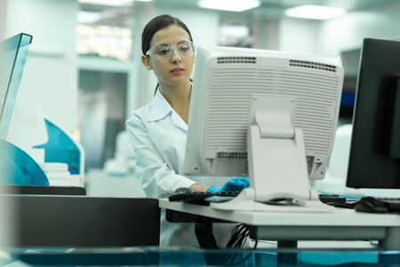 Lets work. Serious brunette woman wearing protective glasses while concentrating on taskの写真素材