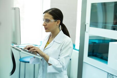 Be serious. Attentive young microbiologist staring at monitor while testing computer
