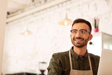 Handsome entrepreneur. Handsome entrepreneur wearing glasses sitting in cafeteria with modern...