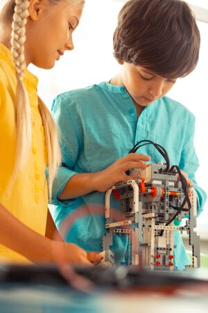 Helping each other. Two serious concentrated classmates building a model out of construction set...