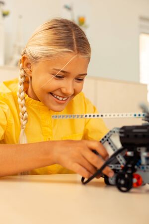 Happy at school. Elementary school girl smiling building a helicopter model of construction set in the science lesson.の写真素材
