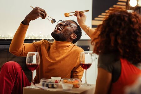 Handsome dark-skinned male person opening mouth while enjoying tasty roll