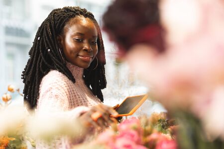 Like it. Cheerful dark-skinned florist expressing positivity while choosing her favorite flowersの写真素材