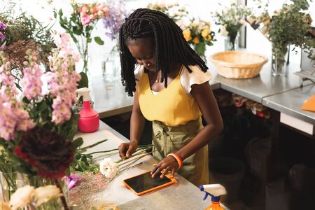 Attentive female person bowing head while looking at her gadgetの写真素材